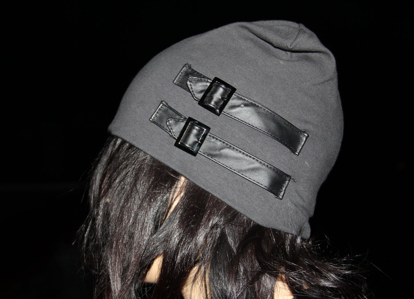 Person wearing a gray beanie with reflective accents against a dark background