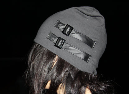 Person wearing a gray beanie with reflective accents against a dark background